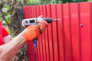 Metal Fence being installed by a worker with a power tool